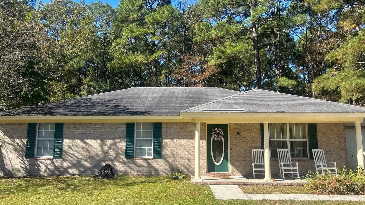 Brick ranch home under tall pines on a wooded Bloomingdale GA lot, documented during a roof inspection