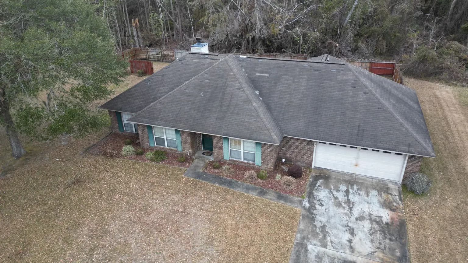 Storm-damaged asphalt shingle roof on a Hinesville GA home in Liberty County after a tropical system