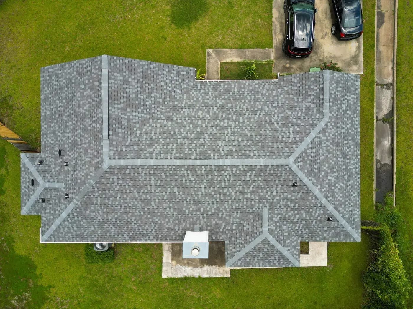 Aerial view of the completed Coastal Granite shingle roof surrounded by a wooded yard.